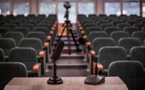 Sleek corporate conference room featuring a wall-mounted flat-screen video display and high-end polished wood boardroom table.