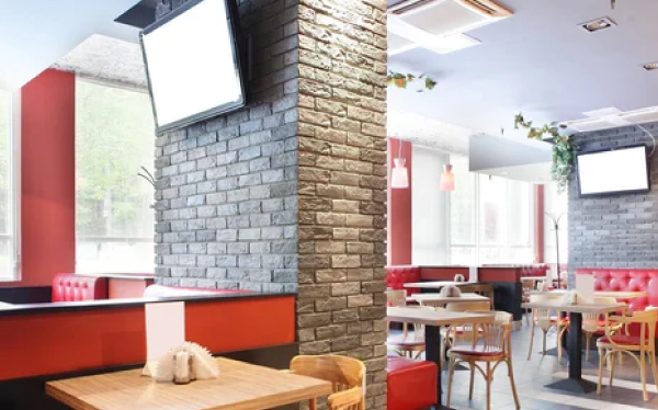 Integrated commercial video installation with multiple digital screens mounted on brick pillars in a modern restaurant dining area.