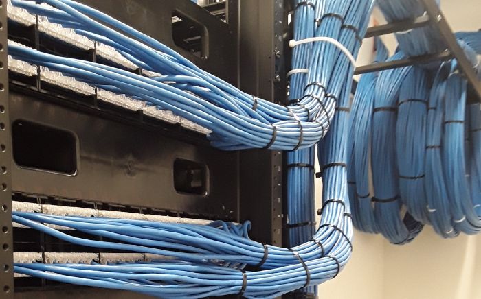 Network rack with CAT 6 cables and patch panels in a data center.